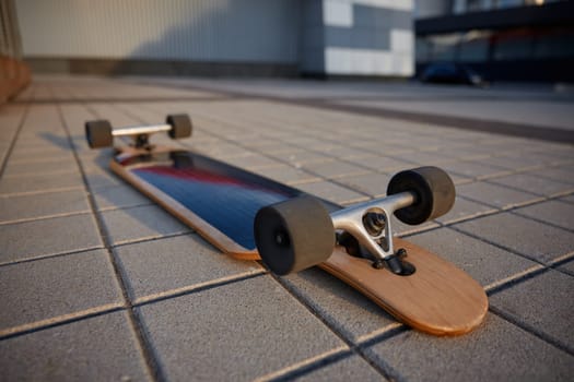 Skateboard on asphalt road with wheel upwards and shallow depth of field. Old style longboard for extreme sports activity