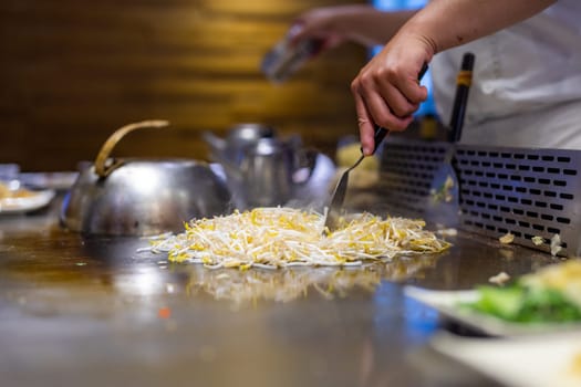 Teppanyaki chef preparing food on hot metal plate