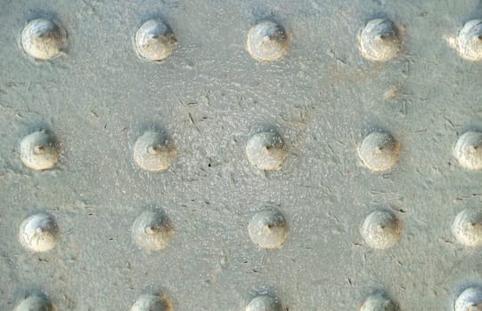 Grey glossy metal old surface with peeling paint and decorative bumps on the surface