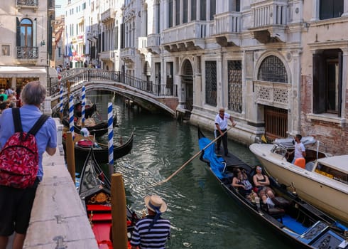 Venice, Italy - September 5, 2022: One of the most recognizable tourist attractions in the world - a gondola cruise through the narrow canals in Venice