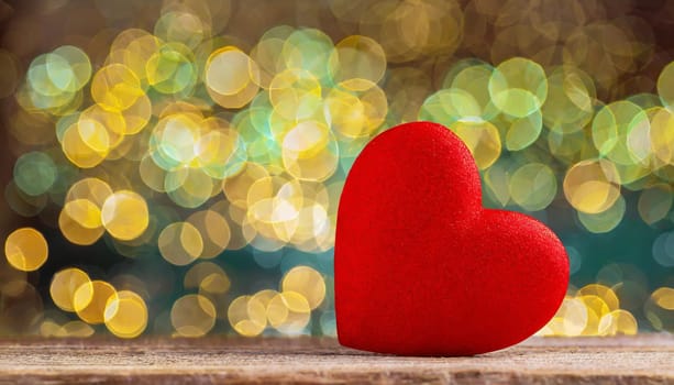 Valentines day composition with red heart against bright bokeh defocused background. Greeting festive card.