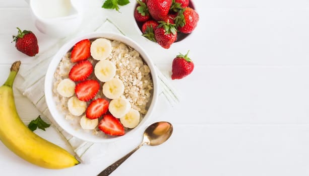 Bowl of oatmeal porridge with strawberry and banana on white table top view. Healthy and die (3)-Enhanced-SR.jpg