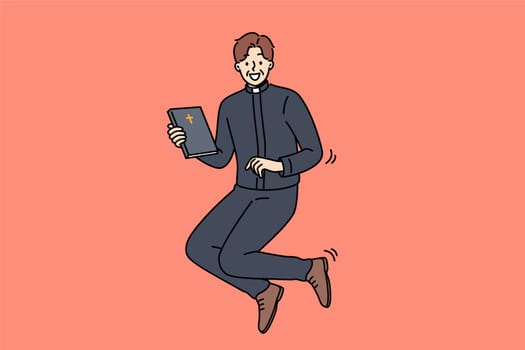 Joyful catholic priest jumps up with bible in hands, inviting you to temple for sunday worship. Happy priest man in religious clothes holding book with christian cross and looking at screen smiling