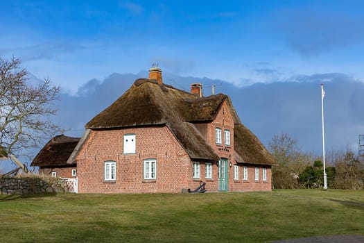 List, Germany - February 17, 2021: typical red brick Frisian house with thatched roof on Sylt island in List village, Germany.