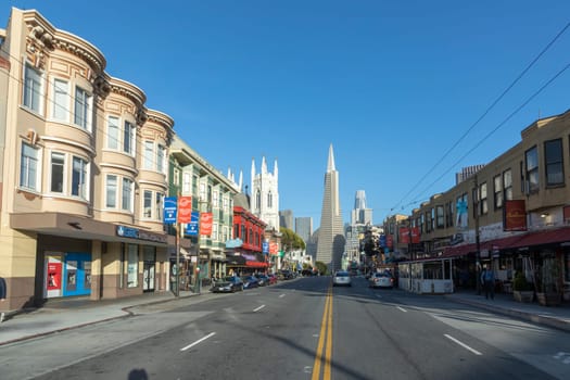San Francisco, USA - May 18, 2022:  old houses in downtown San Francisco in bright light with view to transamerica pyramid.