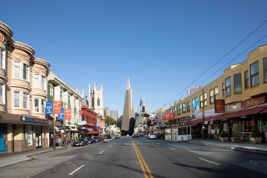 San Francisco, USA - May 18, 2022:  old houses in downtown San Francisco in bright light with view to transamerica pyramid.