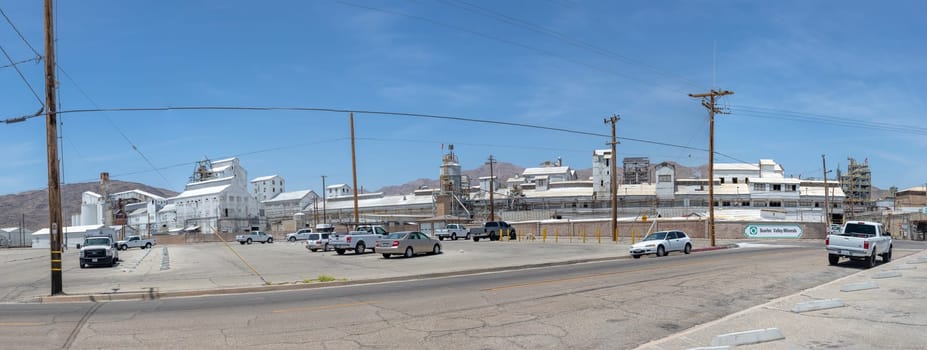 Trona, USA - May 22, 2022: view to village of Trona in the Mojave desert. with the factory of searless valley Minerals.. The ground os covered with white mineral dust from the mine.