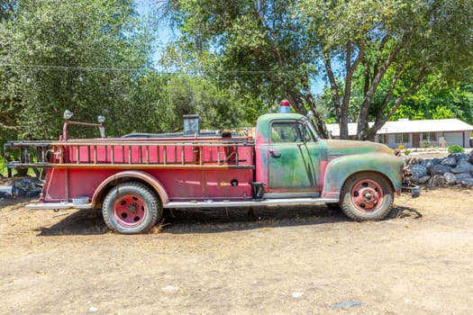 Three Rivers, USA - May 21, 2022: old vintage dirty  fire engine vintage car at an outdoor loam parking lot in three rivers.