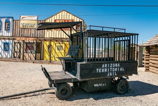 Seligman, USA - May 26, 2022: old historic wild west facade with livery and tonsorial of Doc Holliday under clear blue sky in Seligman.and jail transportation coach.