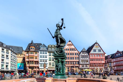 Frankfurt, Germany - March 28, 2023: Lady justice at Frankfurt Roemer with old half timbered houses in background.
