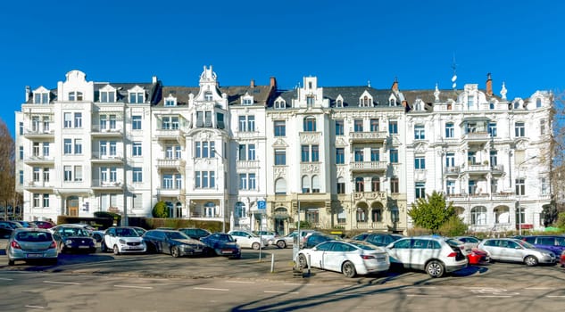 Wiesbaden, Germany - February 27, 2023:  facade of old historic house from the 18th century with balconies and a parking lot in front.