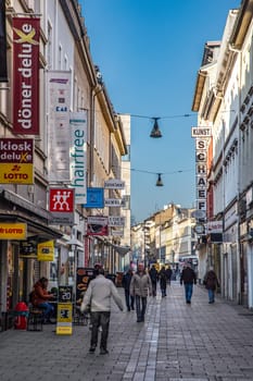 Wiesbaden, Germany - March 2, 2023: people go shopping at Faulbrunnenstrasse - engl: rotten fountain street -  with historic 19th century facades downtown Wiesbaden in the old town.