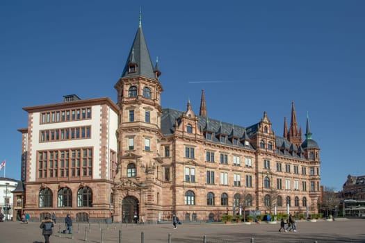Wiesbaden, Germany - March 2, 2023: people at the market square with historic old town hall under blue sky.