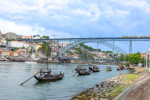 Porto, Portugal - May 3, 2023: old vinery ships at river Duoro with skyline of Porto in background and bridge ponte luis I in Gaia, Porto, Portugal.