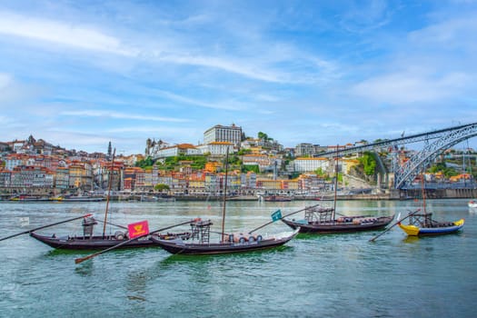 Porto, Portugal - May 3, 2023: old vinery ships at river Duoro with skyline of Porto in background and bridge ponte luis I in Gaia, Porto, Portugal.
