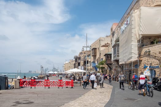 Tel Aviv, Israel - May 18, 2023: people enjoy walking at the beach  promenade of the beautiful old town of Tel Aviv.