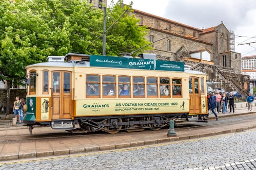 Porto, Portugal - May 4, 2023: Porto, vintage Portuguese traditional city tram Infante 1 designed with advertisements with the view on the river