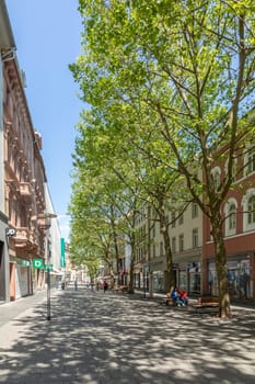 Wiesbaden, Germany - May 18, 2023: pedestrian street in midday sun with trees and shops in the historic classicistic buildings.