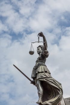 Frankfurt, Germany - May 24, 2023: lady justice in Frankfurt with sword and cloudy sky as symbol for justice and law