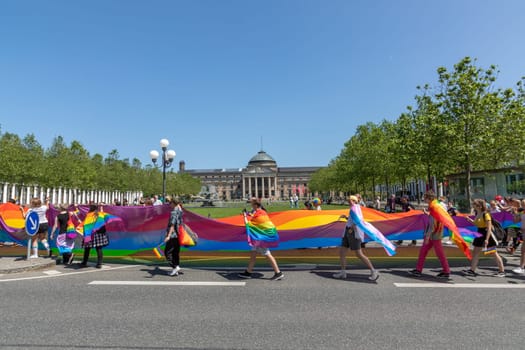 Wiesbaden, Germany - May 27, 2023: people enjoy the christopher street parade in Wiesbaden with rainbow flags and beaufiful costumes.