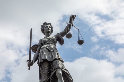 Frankfurt, Germany - May 24, 2023: lady justice in Frankfurt with sword and cloudy sky as symbol for justice and law