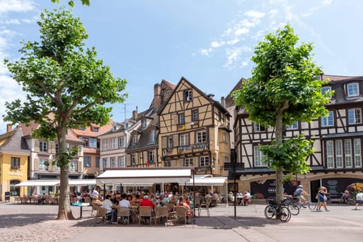 Colmar, France - June 21, 2023: Dominican square in Colmar, France with half timbered houses and tourists, enjoying sitting in the  cafes at a summer day.