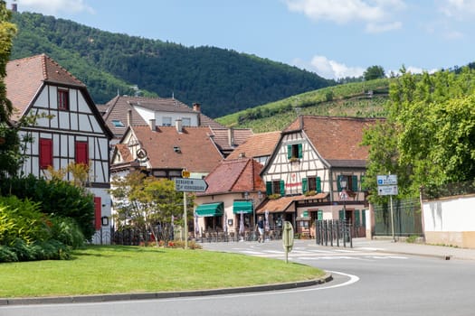 Ribeauville, France - June 23, 2023: A picturesque colorful street of half-timber buildings with shops and cafes in the village of Ribeauville, in the Alsace region.