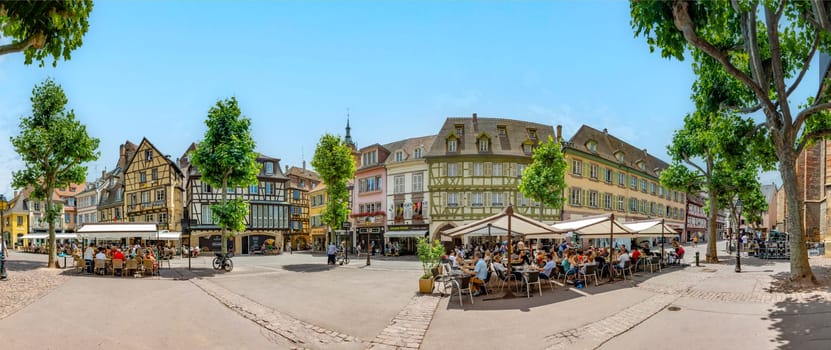 Colmar, France - June 21, 2023: Dominican square in Colmar, France with half timbered houses and tourists, enjoying sitting in the  cafes at a summer day.