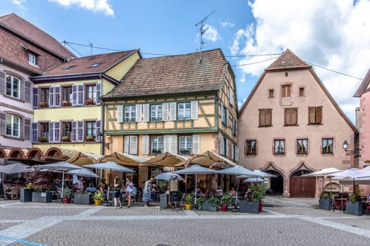 Ribeauville, France - June 23, 2023: A picturesque colorful street of half-timber buildings with shops and cafes in the village of Ribeauville, in the Alsace region.