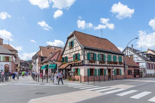 Ribeauville, France - June 23, 2023: A picturesque colorful street of half-timber buildings with shops and cafes in the village of Ribeauville, in the Alsace region.
