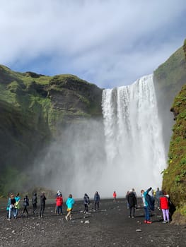 Skógafoss, Iceland -July 19, 2023: Tourists walking towards the Skógafoss waterfall in summer.