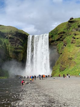 Skógafoss, Iceland -July 19, 2023: Tourists walking towards the Skógafoss waterfall in summer.