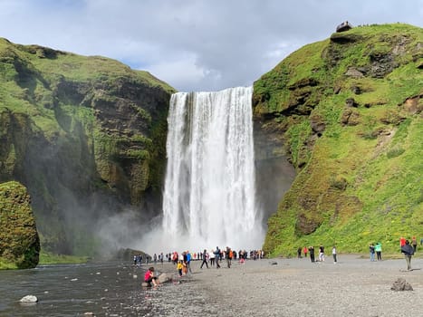 Skógafoss, Iceland -July 19, 2023: Tourists walking towards the Skógafoss waterfall in summer.