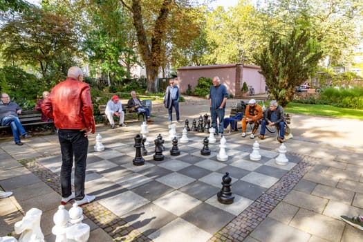 Frankfurt, Germany - October 10, 2023: people enjoy playing chess in the von Bethmann park in Frankfurt, Germany