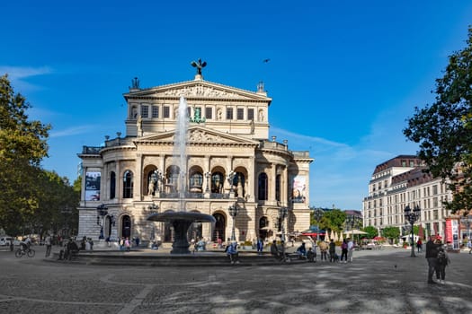 Frankfurt, Germany - October 10, 2023: view of old opera house and people sitting at fountain in Frankfurt, Germany
