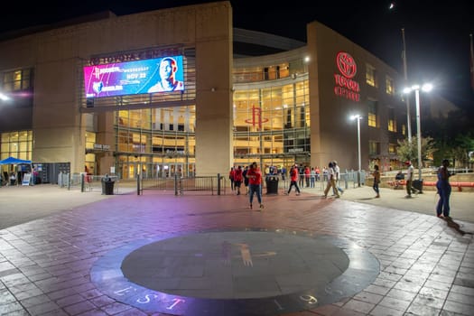 Houston, USA - October 20, 2023: nightview of downtown Toyota center in Houston. People hurry to entrance to join the Houston rockets basketball match.