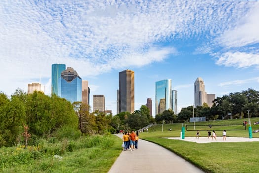 Houston, USA - October 22, 2023: people enjoy scenic view to skyline of Houston, Texas in morning light from Buffalo bayou park. Some play volleyball.