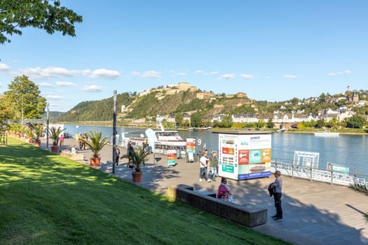Koblenz, Germany - September 24, 2023: people promenade at river Rhine with view to historic fortress Ehrenbreitstein in Koblenz.