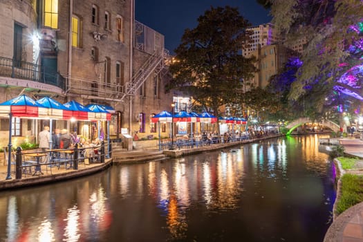 San Antonio, USA - October 31, 2023:  The San Antonio River Walk by night with illuminated trees and restaurants. City park and pedestrian street in San Antonio, Texas. USA
