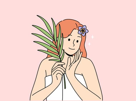 Woman with sprig of medicinal plant used for cosmetic purposes, stands in bath towel and rejoices at effect of using cream. Woman recommends using eco-masks and creams based on organic herbs