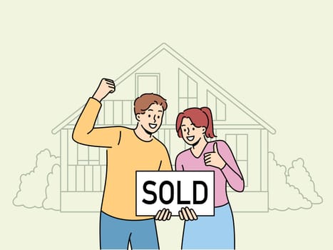 Happy couple is standing near house with inscription sold, rejoicing in sale of real estate at bargain price. Satisfied man and woman rejoice in profitable real estate deal and make victory gestures