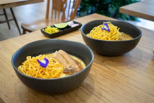 Thai noodles Khao Soi, spicy curry with seasoning on table, stock photo
