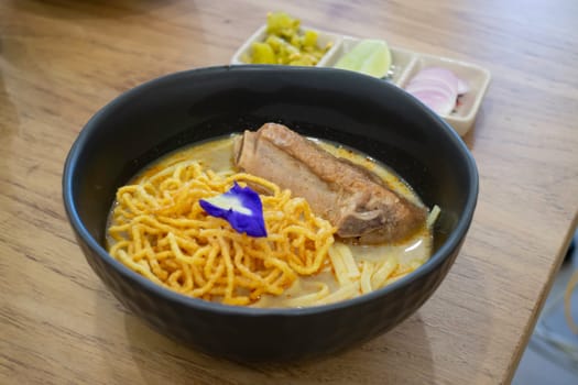 Thai noodles Khao Soi, spicy curry with seasoning on table, stock photo