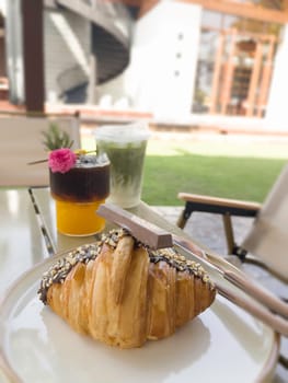Single chocolate croissant and iced drink on table, stock photo