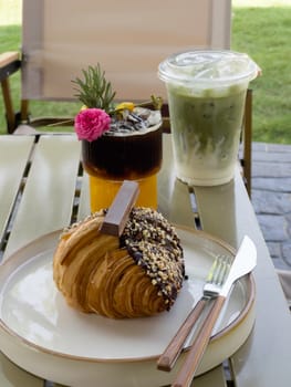 Single chocolate croissant and iced drink on table, stock photo