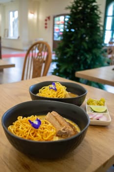 Thai noodles Khao Soi, spicy curry with seasoning on table, stock photo