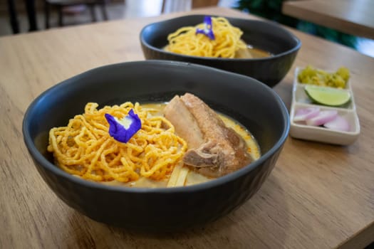 Thai noodles Khao Soi, spicy curry with seasoning on table, stock photo