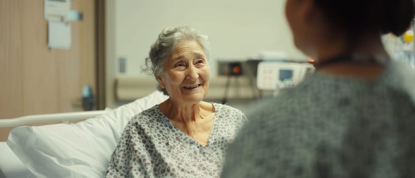 A senior woman's warm smile fills the hospital room as she chats with a caregiver, her spirit undiminished by her surroundings