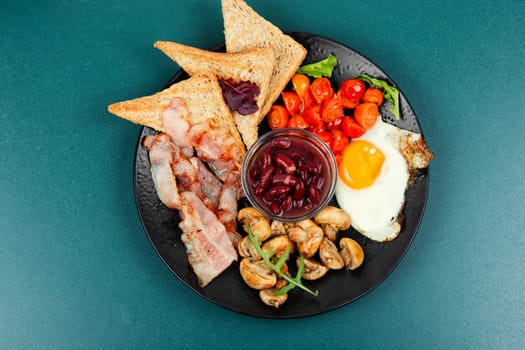 English breakfast: fried egg, fried bacon,vegetables, beans and toast on a plate.