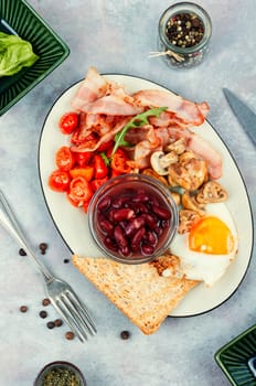 Fried bacon and eggs, toast and beans and vegetables. American Breakfast.